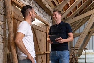 Zwei Männer stehen in einem älteren Stall und besprechen sich
