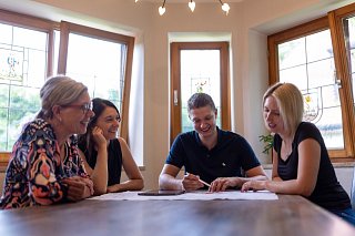 Vier Personen sitzen an einem Tisch und blicken auf einen Bauplan
